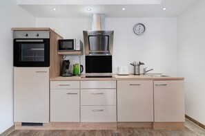 Eine moderne Küche mit eingebauten Geräten, Holzschränken und einer Uhr an der Wand.