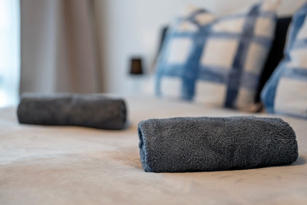 A neatly made bed with a dark grey blanket and a pillow in a hotel room.