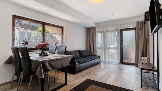 Un salon moderne comprenant un canapé, une table à manger, des chaises et un téléviseur.