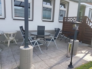Une terrasse extérieure avec une table ronde et des chaises, une petite table ronde et un lampadaire.