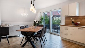 Een moderne keuken met een eettafel, stoelen en een kroonluchter.