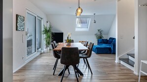 Een moderne eethoek met een houten tafel, zwarte stoelen en een hanglamp.