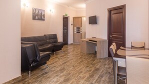 En moderne hotellobby med en lædersofa, et lille barområde og en træreception.