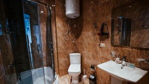 Et moderne badeværelse med en glasvæg omkring bruseniche, toilet og håndvask.