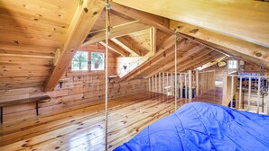 A wooden cabin with a loft bedroom, a wooden floor, and a blue tarp on the floor. - Bellevue Log Cabin w/ Gas Grill & Creek Access (Bellevue)