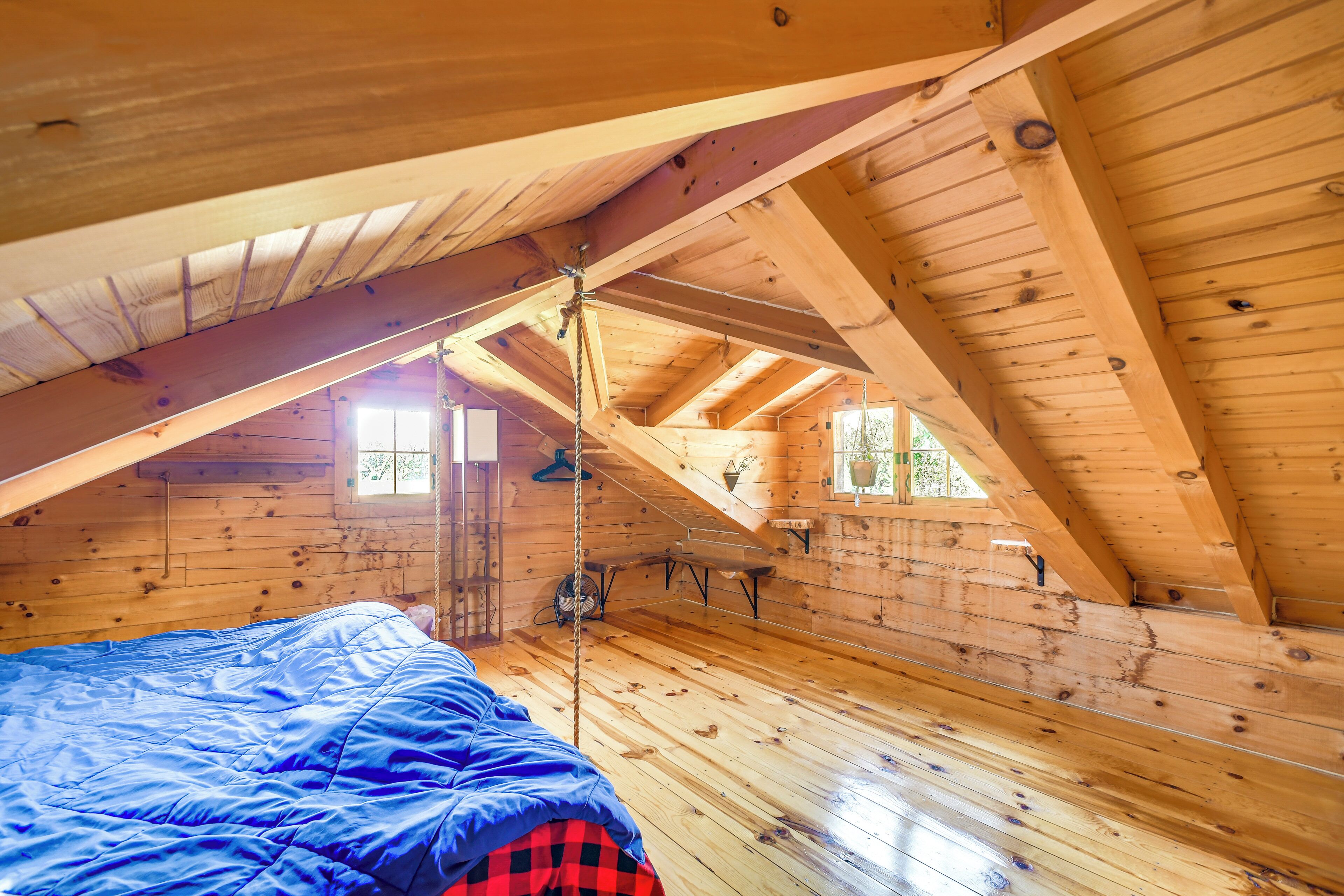 Une cabane en bois avec une chambre à coucher aménagée en mezzanine, une balançoire et une petite fenêtre.