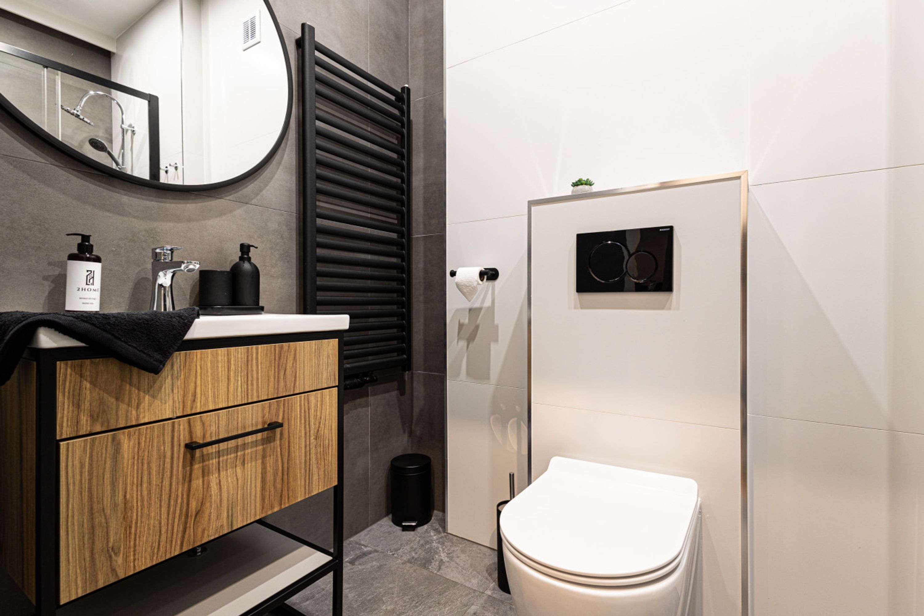 Ein modernes Badezimmer mit einem Holzbettchen, einer Toilette, einem Handtuchhalter und einem Spiegel.