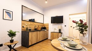 Una cocina moderna con encimera de madera, horno empotrado, un lavamanos y un comedor con una mesa redonda para dos.
