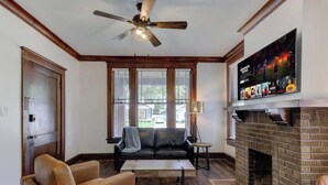 Ein Wohnzimmer mit Kamin, Deckenventilator, Fernseher und einer Couch.