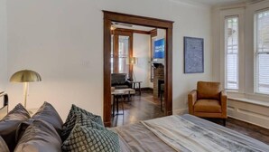 Ein Schlafzimmer mit einem Bett, einem Ledersessel, einer Couch, einem Schreibtisch und einem Kamin.