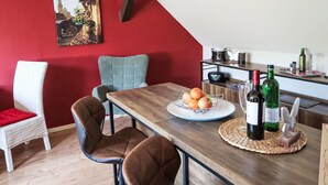 Un comedor con una mesa de madera, dos sillas, una pared roja y un cuadro.