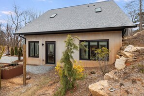 A modern two-story house with a sloped roof, large windows, and a stone foundation.
