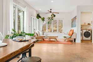 A modern living room with a wooden dining table, two sofas, a coffee table, and a ceiling fan.