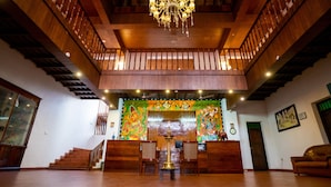 Un vestíbulo espacioso con una escalera de madera, un candelabro y un mural colorido en la pared.