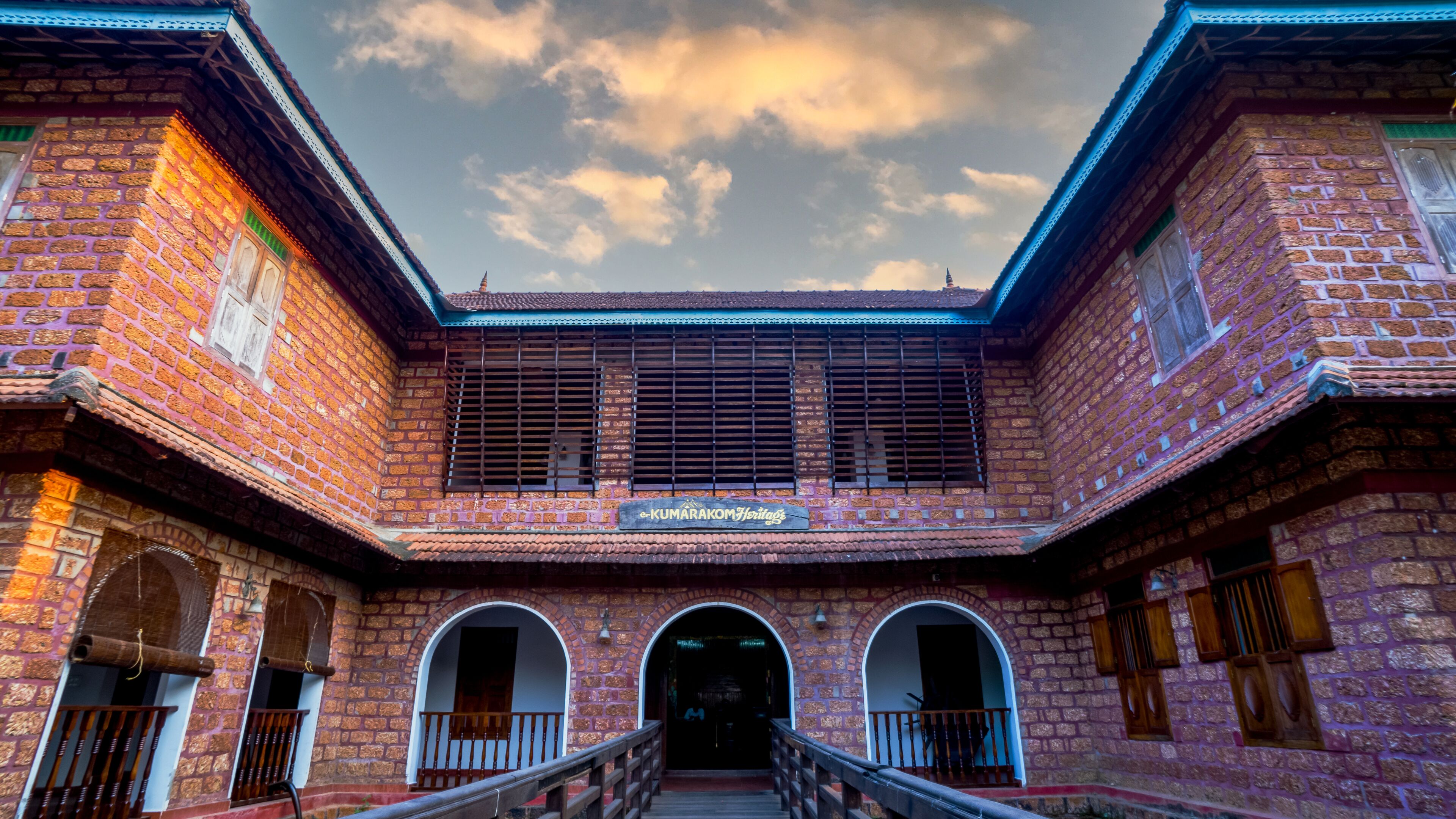A traditional brick building with a sign reading "e-KUMARAKOM Heritage".