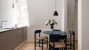 Una cocina moderna con una mesa redonda, sillas negras y un jarrón con flores blancas.