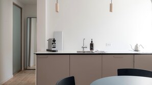 Cocina moderna con una isla central, un lavamanos y un hervidor. Hay dos lámparas colgantes sobre la isla.