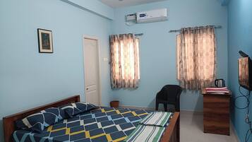 A room with a bed, a desk, a chair, a television, and curtains.