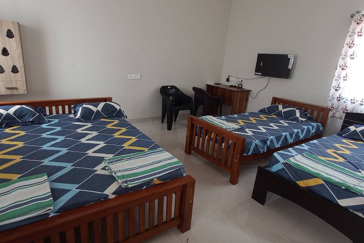 Ein Zimmer mit zwei Holzbetten, einem Schreibtisch, einem Stuhl und einem Fernseher an der Wand.