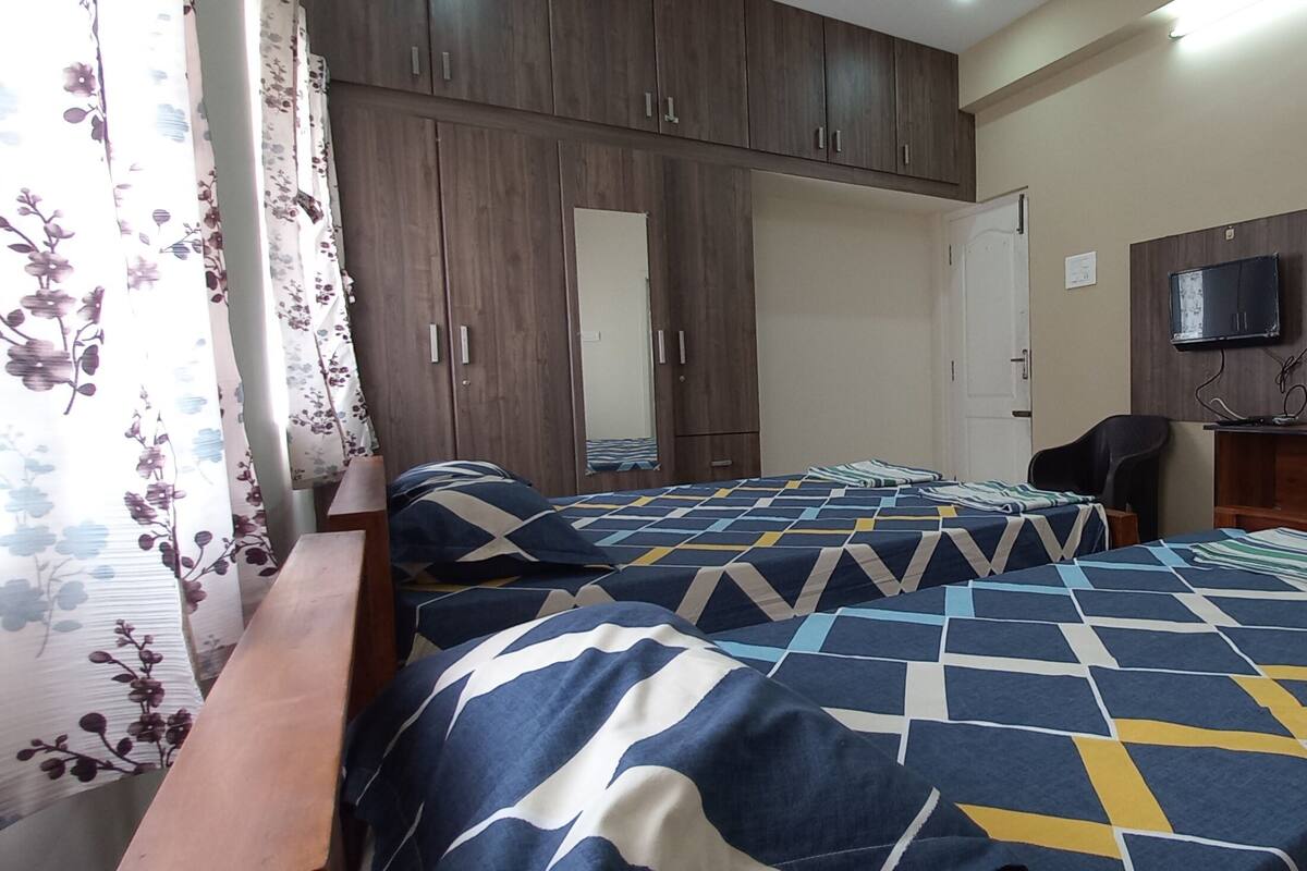 Ein Schlafzimmer mit zwei Betten, einem Holzschrank und einem Fernseher an der Wand.