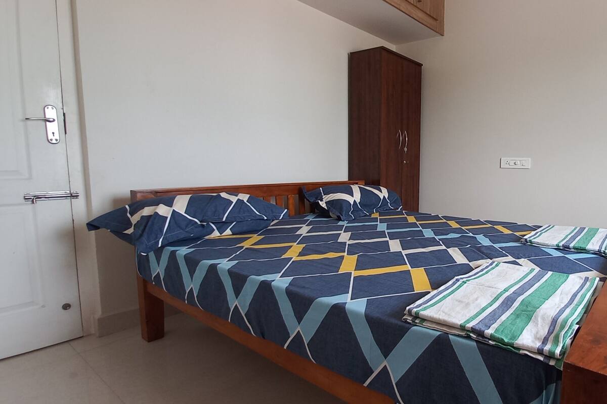 Ein Schlafzimmer mit Bett, Kleiderschrank, Spiegel und Stuhl.
