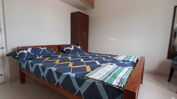 Un dormitorio con cama, armario, espejo y silla.