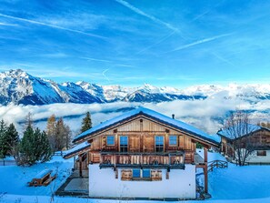 A wooden chalet with a balcony, surrounded by snow-covered mountains and a clear sky. - Gingembre 12 by Interhome (Nendaz)