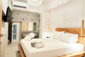 A modern bedroom with a large bed, a wooden headboard, a bedside table, a mirror, and a wall-mounted TV. - Design Superior Apartment with Jacuzzi, Sea View, Shared Infinity Pool, Bar, Gym (C965+8J Mykonos, Greece)