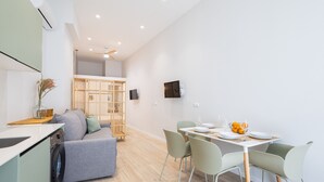 Eine moderne Küche mit integriertem Waschmaschine, einem Essbereich mit Tisch für zwei Personen und einer Sitzecke mit Sofa.