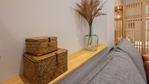 A wooden shelf with woven baskets and a glass vase with dried plants.