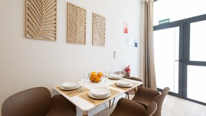 A dining area with a table set for four, including plates, cutlery, and a fruit bowl. There are three wall-mounted decorative panels above the table.