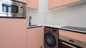 Une cuisine compacte équipée d’un four à micro-ondes, d’un lave-vaisselle et d’un lave-linge.