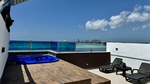 A rooftop terrace with a pool, lounge chairs, and a view of the ocean and port. - Aquamarine Retreat Penthouse Boca Chica (Boca Chica)