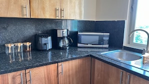 A kitchen with wooden cabinets, a microwave, a coffee maker, and a sink. - Aquamarine Retreat Penthouse Boca Chica (Boca Chica)