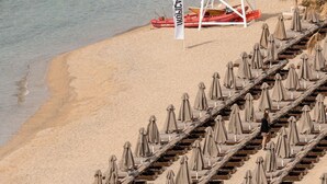 En strand med rækker af liggestole og et vagttårn.