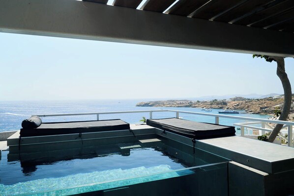 Une piscine à débordement offrant une vue sur la mer et dotée d’une balustrade blanche.