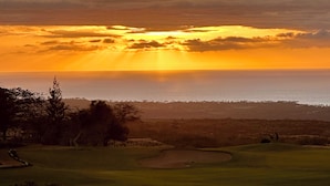 A golf course with a sunset view, a body of water, and a distant shoreline. - NEW- Expansive Ocean View- Pool/Tennis/Pickleball (Waikoloa Village)