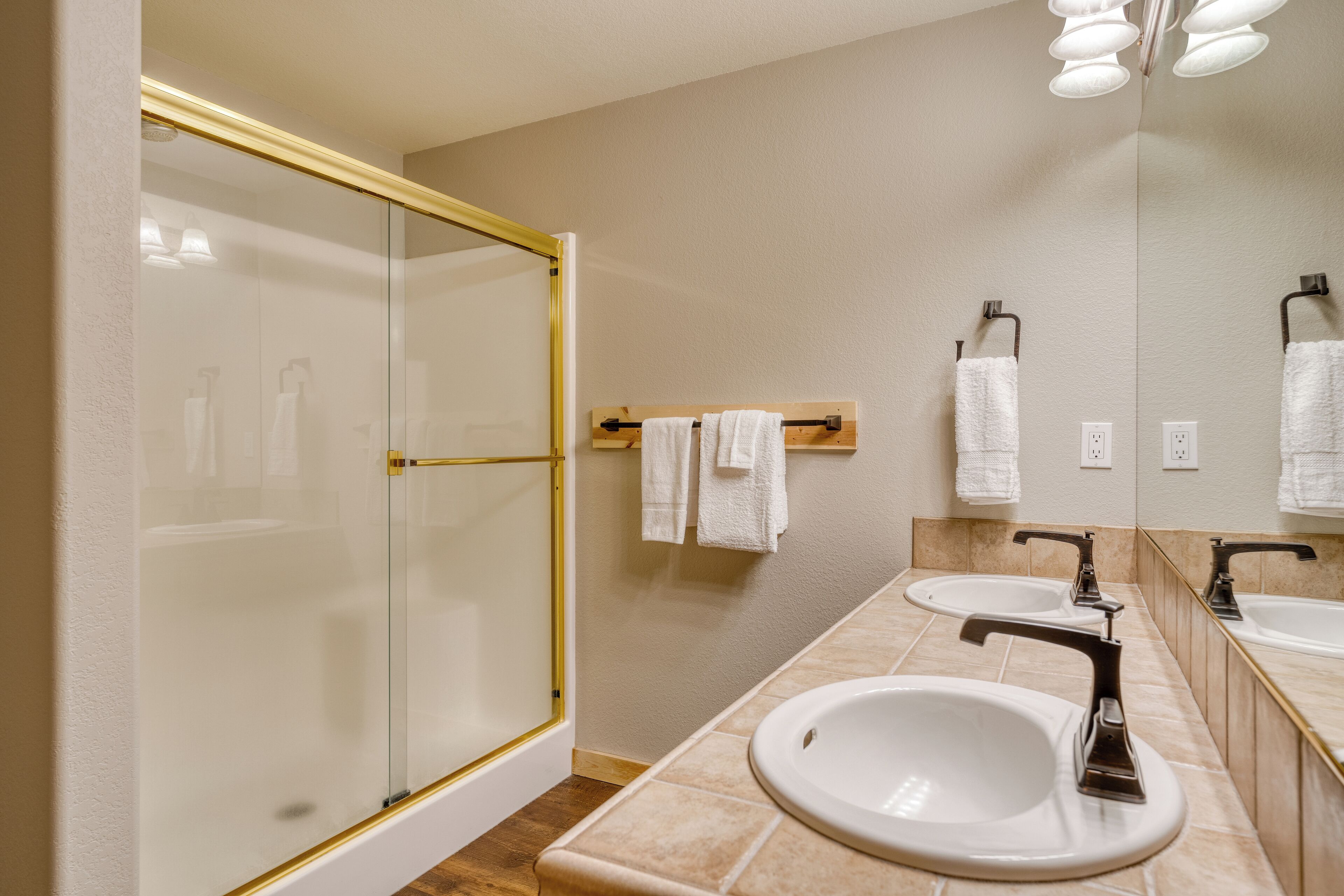 A modern bathroom with a glass shower enclosure, two sinks, and a large mirror.