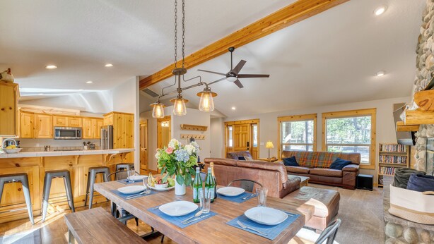 A spacious kitchen with wooden cabinets, a dining table set for four, and a ceiling fan. - Quail by AvantStay | Great Location + Game Room, Hot Tub, & Deck! (Sunriver)