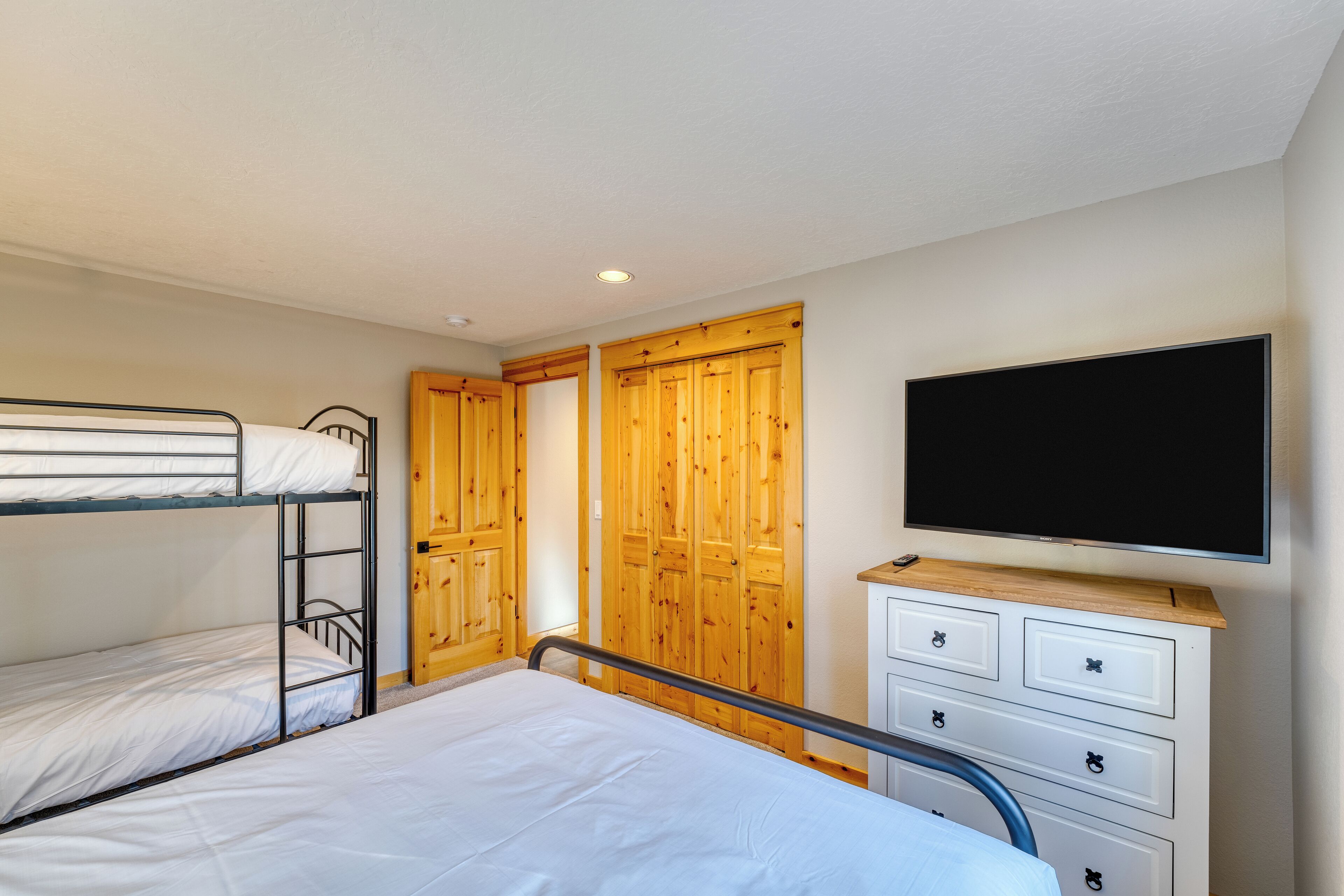 A bunk bed room with a television and a dresser.