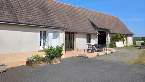 A two-story house with a tiled roof, a front porch, and a small garden area with plants and a table. - Discover the Châteaux of the Loire (La Ferriere)