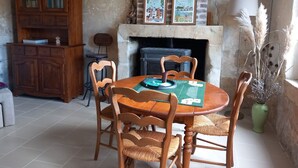 A dining area with a round wooden table, four chairs, a green placemat, and a fireplace. - Discover the Châteaux of the Loire (La Ferriere)