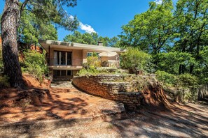 A modern house with a stone staircase leading to a wooden deck, surrounded by trees and a clear sky. - Agréable Havres de Paix à Roussillon (Roussillon)