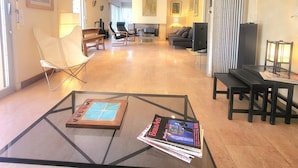 Amplia sala de estar con una mesa de centro de vidrio, un sofá, un televisor y una mesa de comedor con sillas.