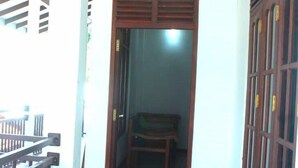 A hallway with a wooden door leading to a room with a bed and a chair. - Thirasara Holiday Resort (Thissamaharama)