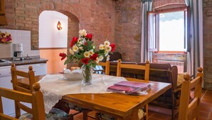 A dining area with a wooden table, chairs, and a vase of flowers. - Apartment in Tuscany with Pool & Garden (Montaione)