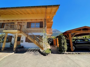 A wooden building with a staircase, a balcony, and a mountain in the background.