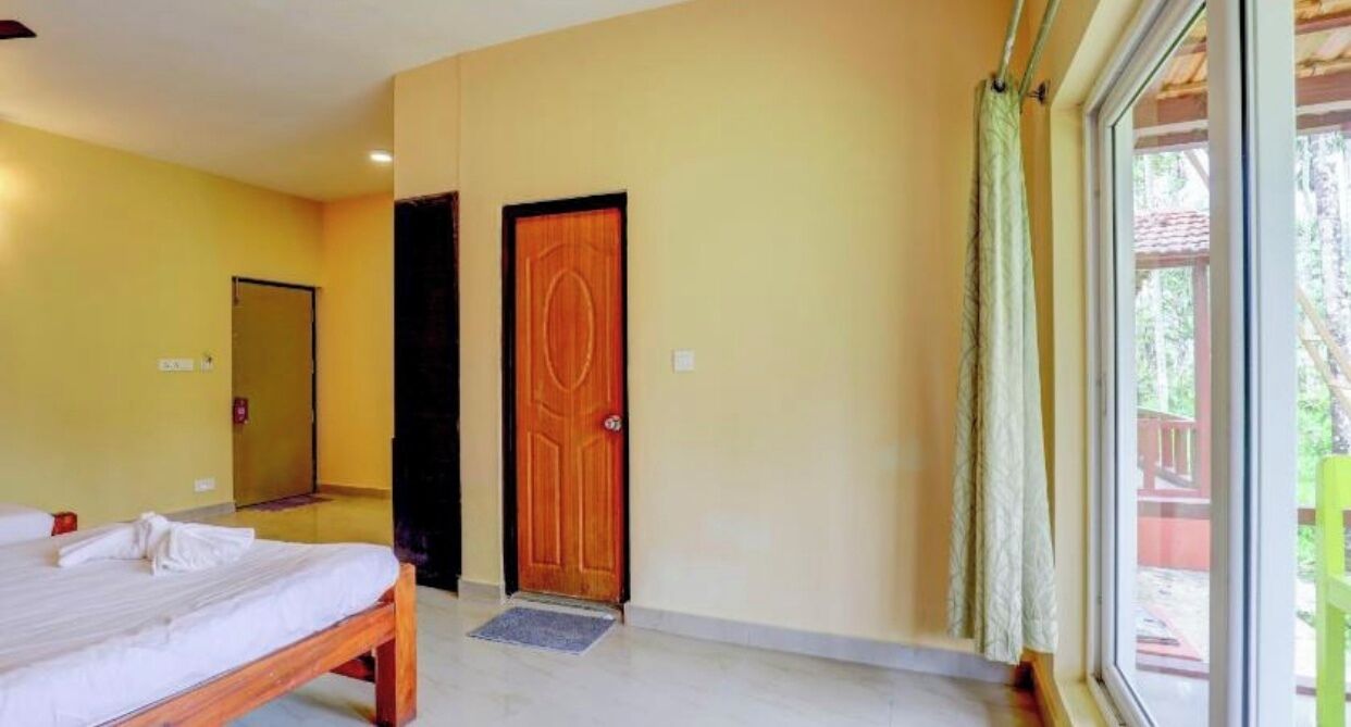 Una habitación de hotel con una cama, una puerta de madera y vistas al exterior.