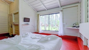 A room with a bed, a television on the wall, a window with curtains, and a red carpet. - Lazo Areca Resort (Madikeri)