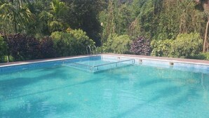 A clear blue pool surrounded by lush greenery. - Lazo Areca Resort (Madikeri)
